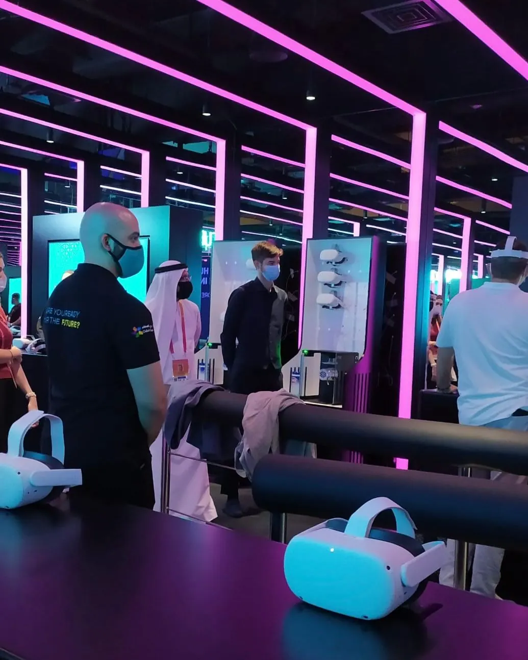 Visitatori e personale nell'area di realtà virtuale di un padiglione a Expo 2020 Dubai, con i visori pronti sul bancone