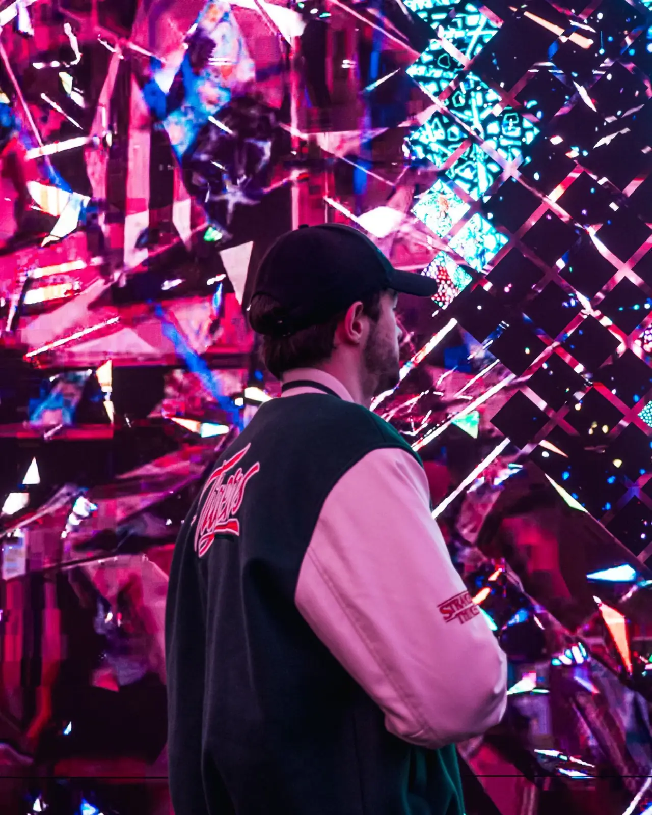 Simone di spalle davanti a un grande schermo LED con immagini luminose e colorate