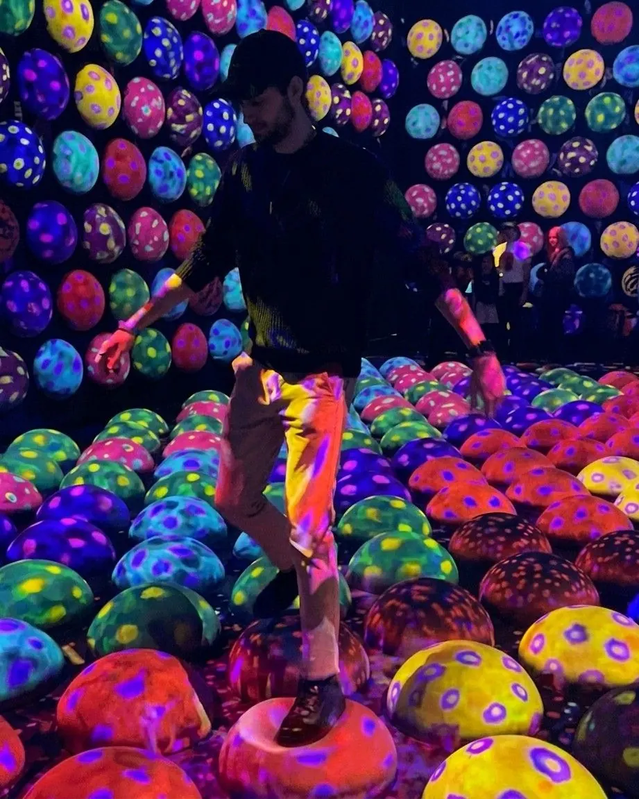 Simone cammina tra le installazioni di luce e colore di un museo digitale immersivo